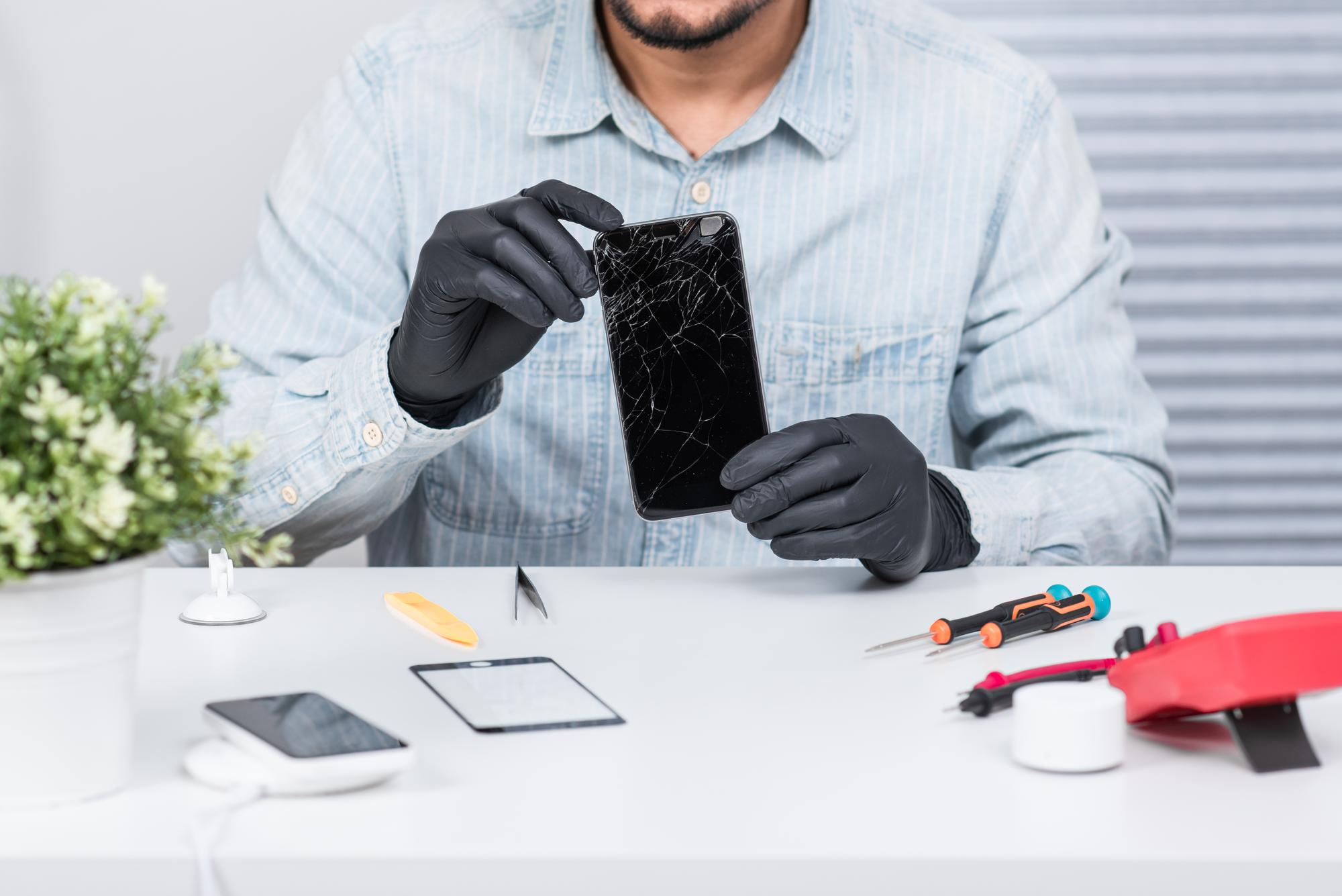 Telefoonreparatie Dokkum — technicus met handschoenen repareert gebroken telefoonscherm